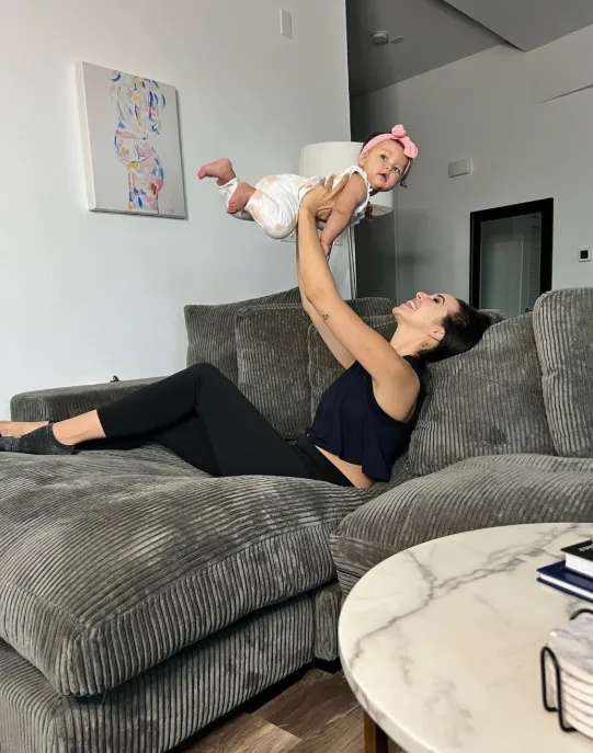 Playing with a baby on a sectional sofa inside a Wallace on Sunset apartment