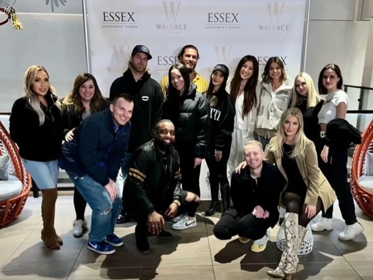 Group photo of guests in front of an Essex Apartment Homes and Wallace step-and-repeat banner at a resident event