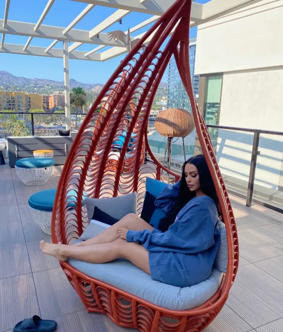 Relaxing in a red woven hanging chair on the rooftop deck in the afternoon sun