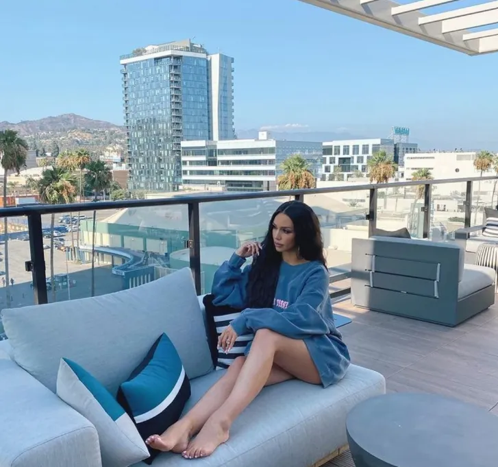 Lounging on a rooftop sofa with the Los Angeles skyline and hills behind